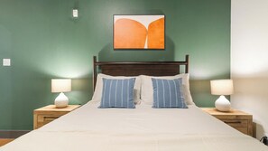Ett hotellrum med en säng, två sängbord och ett konstverk som hänger på väggen.