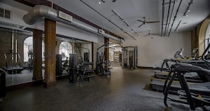 A gym with treadmills, weight machines, and a mirrored wall. - Landing | Spectacular 2BD, Gym, Courtyard (Houston)