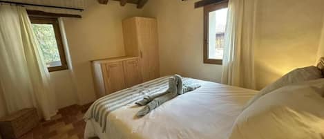 Un dormitorio con una cama, armario de madera y lámpara colgante.
