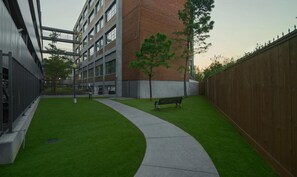 A courtyard with a curved pathway, a bench, and a tree. - Landing | Beautiful 1BD, Gym, Courtyard (Houston)