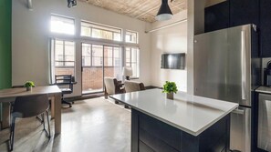 A modern kitchen with a large island, a built-in refrigerator, and a dining area with chairs and a table. - Landing | Beautiful 1BD, Gym, Courtyard (Houston)