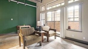 A room with two chairs, a small table, a lamp, and a green wall. - Landing | Chic 1BD, Courtyard, Gym (Houston)