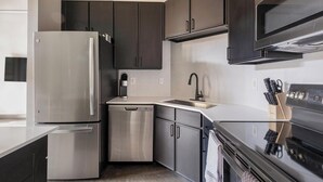 A modern kitchen with stainless steel appliances, a dishwasher, and a sink. - Landing | Beautiful 1BD, Gym, Courtyard (Houston)