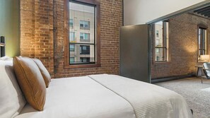 Une chambre d’hôtel avec un grand lit, un mur en briques et une fenêtre.