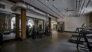 Een fitnessruimte met loopbanden, krachttoestellen en een spiegelwand.