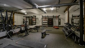 Un gimnasio con equipo de ejercicio, espejos y un soporte para pesas.