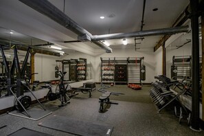 A gym with exercise equipment, mirrors, and a weight rack. - Landing | Amazing 1BD, Courtyard, Gym (Houston)