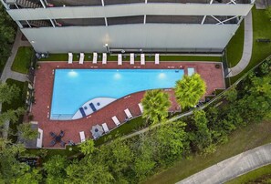 An aerial view of a hotel with a swimming pool, lounge chairs, and a covered area. - Landing | Amazing 1BD, Courtyard, Gym (Houston)