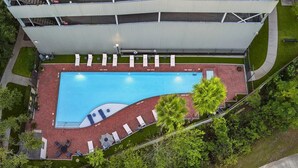 Vista aérea de un hotel con piscina, sillas de descanso y una zona cubierta.