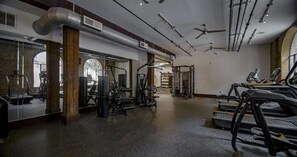 A gym with treadmills, weight machines, and a mirrored wall. - Landing | Incredible 1BD, Gym, Courtyard (Houston)