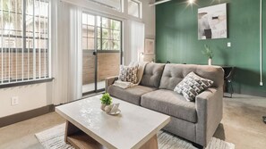Ein Wohnzimmer mit einer Couch, einem Couchtisch und einem Fenster mit Jalousien.