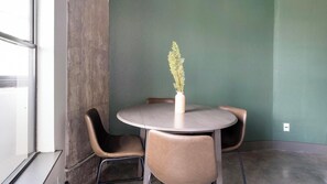 A small round table with a vase of flowers, two chairs, and a green wall. - Landing | Amazing 2BD, Gym, Courtyard (Houston)
