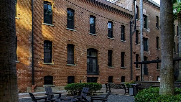 Un patio con edificios de ladrillo, asientos al aire libre y un brasero.