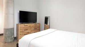 Un dormitorio con una cama, un aparador de madera, un televisor y un espejo.