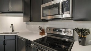 A modern kitchen with stainless steel appliances, including a microwave, oven, and dishwasher. - Landing | Modern 1BD, Courtyard, Gym (Houston)