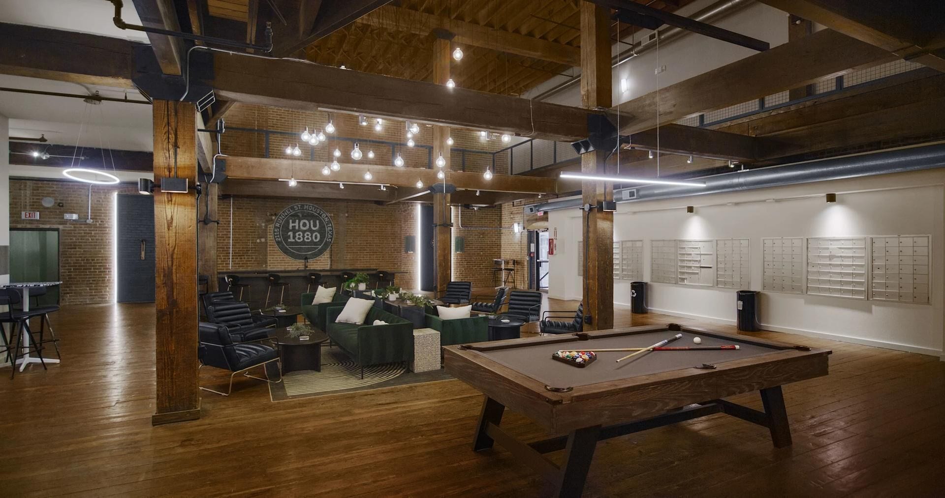 A billiards room with a pool table, seating area, and a brick wall with a date plaque.