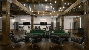 Un salon spacieux avec de hauts plafonds, des poutres apparentes et des luminaires suspendus.