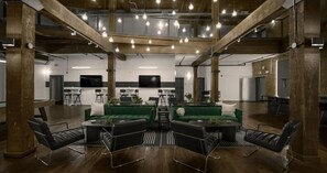 A spacious lounge with high ceilings, exposed beams, and hanging light fixtures. - Landing | Modern 1BD, Gym, Courtyard (Houston)