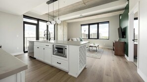 A modern kitchen with a large island, built-in appliances, and large windows offering views of the city. - Landing | Beautiful 2BD, Yoga Studio, Gym (Denver)