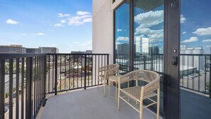 A balcony with a view of the city, two wicker chairs, and a glass door. - Landing | Beautiful 2BD, Yoga Studio, Gym (Denver)