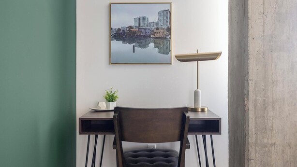 A desk with a chair, a lamp, a framed picture, and a potted plant. - Landing | Amazing 1BD, Gym, Yoga Studio (Denver)