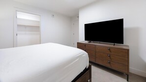 A bedroom with a bed, a dresser, a television, and a closet. - Landing | Amazing 1BD, Gym, Yoga Studio (Denver)