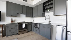 A modern kitchen with grey cabinets, stainless steel appliances, and a white tiled backsplash. - Landing | Amazing 1BD, Gym, Yoga Studio (Denver)