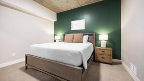 A bedroom with a bed, nightstands, a lamp, and a wall-mounted picture. - Landing | Spectacular 2BD, Rooftop Lounge (Denver)