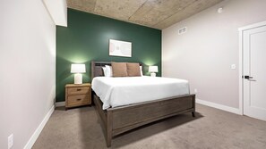 Ein Schlafzimmer mit einem Bett, Nachttischen, einem Wandbild und einer Tür.