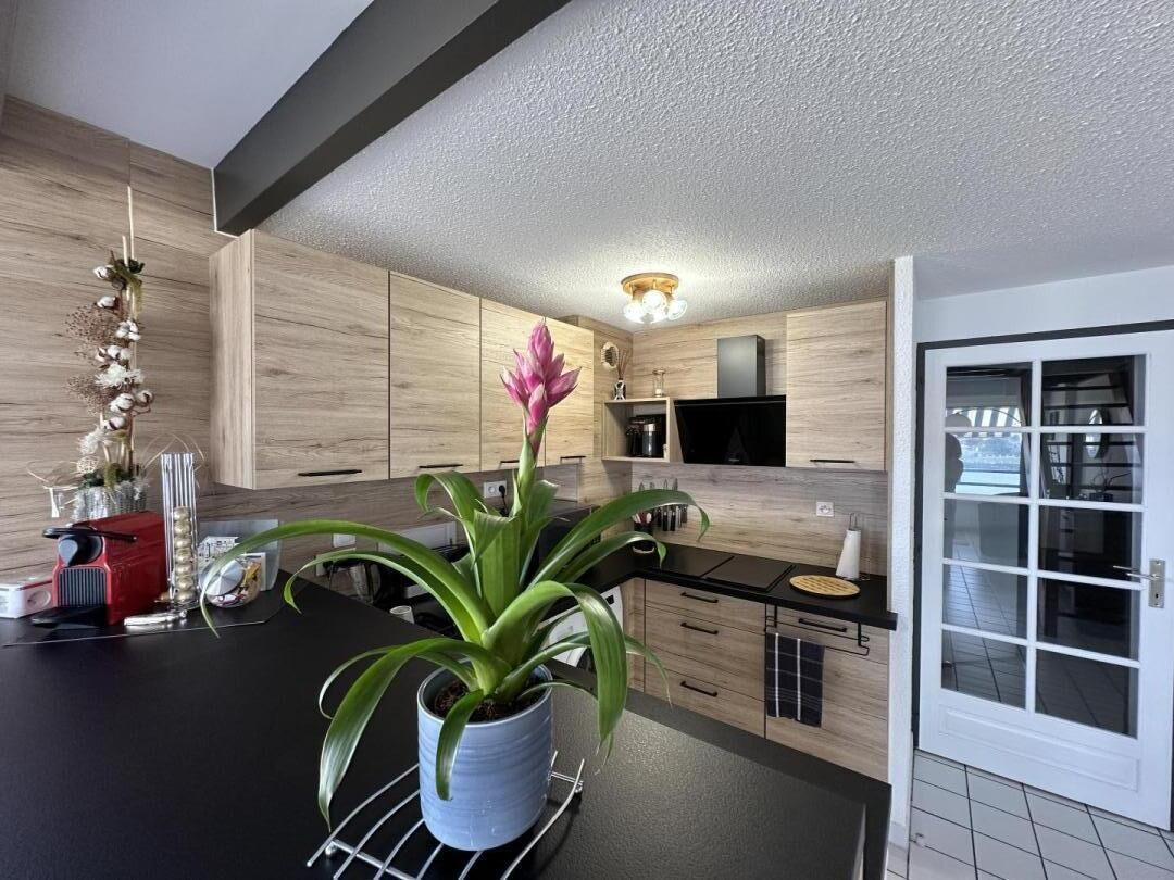 Eine moderne Küche mit Holzschränken, einer schwarzen Arbeitsplatte und einem Blumentopf.