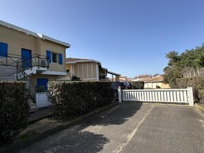 A residential street with houses, a gated driveway, and a clear sky. - Gîte du Courant - MIMIZAN (MIMIZAN)