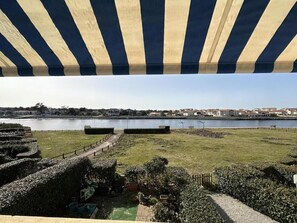 A view of a waterfront area with a grassy lawn, a pathway, and a body of water. - Gîte du Courant - MIMIZAN (MIMIZAN)