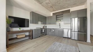 Eine moderne Küche mit grauen Schränken, Edelstahlgeräten und Holzboden.