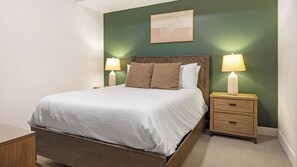 A neatly made bed with a headboard, two bedside tables with lamps, and a framed picture on the wall. - Landing | Stunning 1BD, Clubhouse, Rooftop Lounge (Denver)