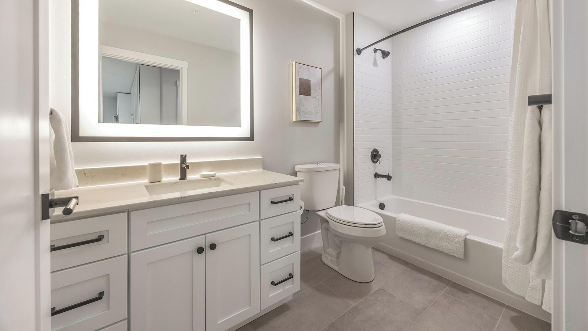 A modern bathroom with a white vanity, sink, and toilet.