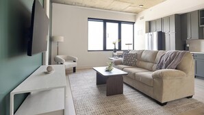 Una sala de estar moderna con un sofá, una mesa de centro y un televisor montado en la pared.