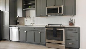 Una cocina moderna con armarios grises, un lavavajillas de acero inoxidable, un microondas integrado y un horno.