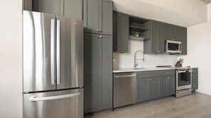 A modern kitchen with stainless steel appliances, grey cabinetry, and a microwave above the counter. - Landing | Stylish 1BD, Yoga Studio, Gym (Denver)