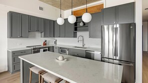A modern kitchen with grey cabinets, a stainless steel refrigerator, and a marble island. - Landing | Stunning 1BD, Gym, Yoga Studio (Denver)