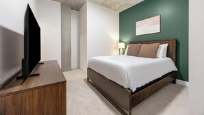 Ein Hotelzimmer mit Bett, Fernseher auf einem Schrank, Nachttisch und einem Wandbild.