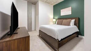 Ein Hotelzimmer mit Bett, Fernseher auf einem Schrank, Nachttisch und einem Wandbild.