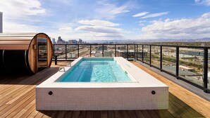 En pool på taget med udsigt over byen, træterrasse og sauna.