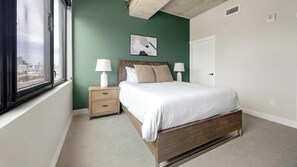 A bedroom with a bed, nightstands, a window, and a city view. - Landing | Spectacular 2BD, Gym, Clubhouse (Denver)