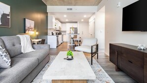 Un salon moderne avec un canapé, une table basse et un téléviseur fixé au mur.