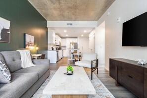 Ein modernes Wohnzimmer mit einer Couch, einem Couchtisch und einem an der Wand befestigten Fernseher.