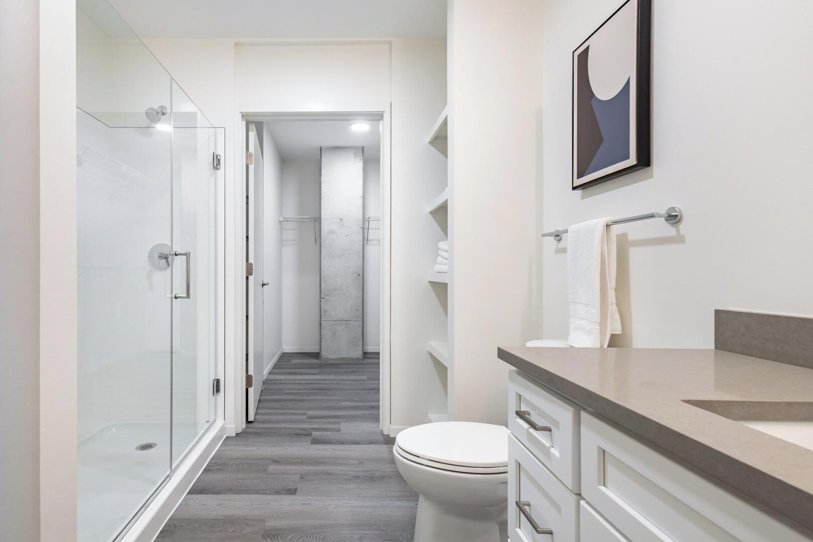 A modern bathroom with a glass shower enclosure, a toilet, and a vanity with a countertop.