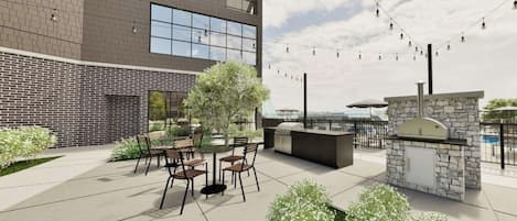 Un patio al aire libre con muro de ladrillo, estación de parrillada y asientos.