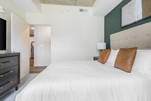 Ein Schlafzimmer mit einem Bett, einer Kommode, einem Nachttisch und einem Wandbild.