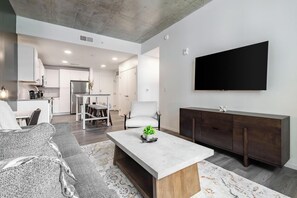 A modern living room with a sofa, coffee table, and a TV mounted on the wall.