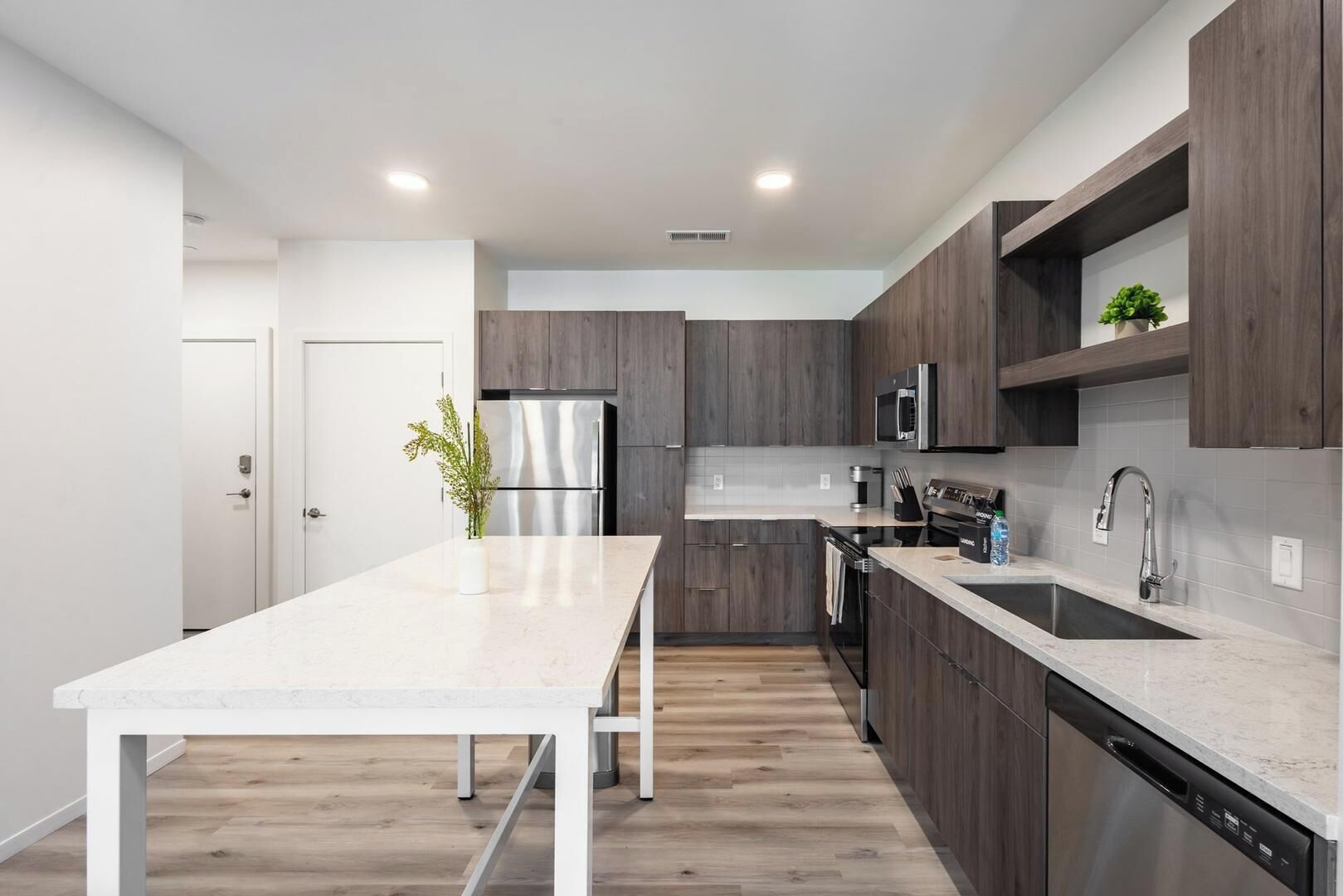 A modern kitchen with a white countertop, stainless steel appliances, and dark wood cabinets.